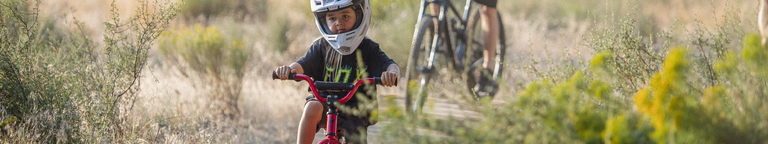 Young rider pedals through the fields on a bike wearing a Fox Racing tee